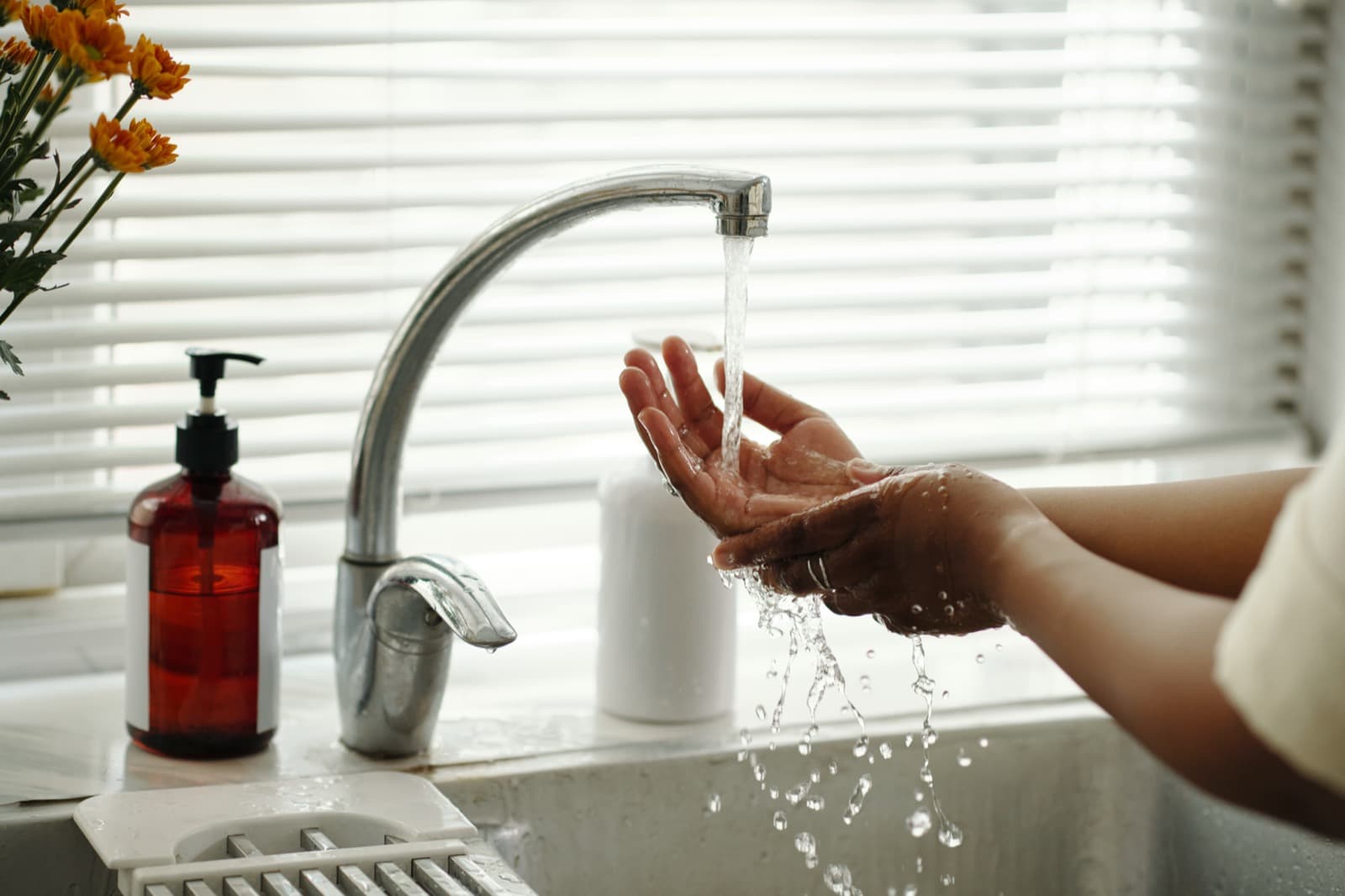 Hands under clean running water from kitchen faucet